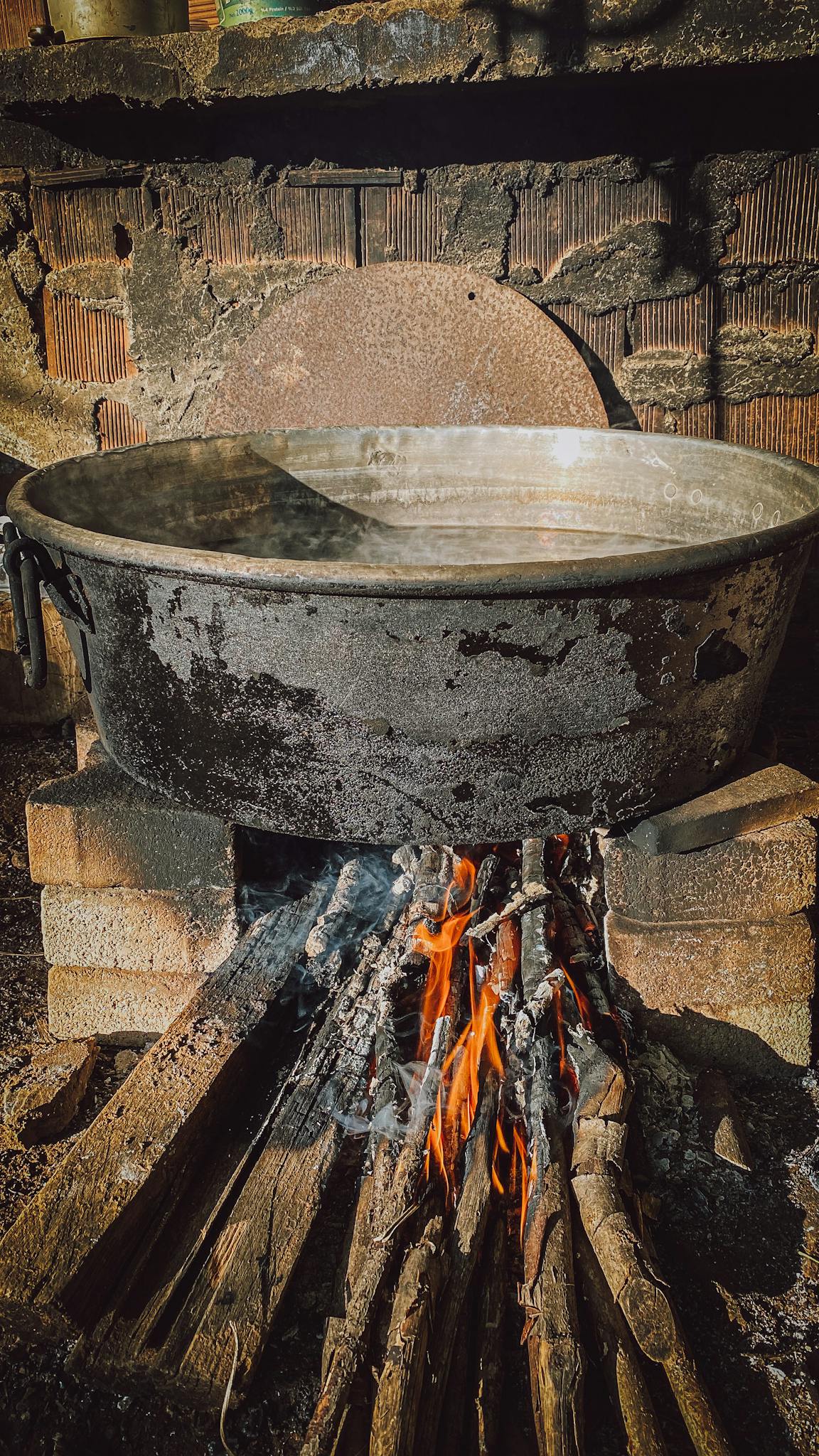 Rugged metal pot on firewood flames for authentic outdoor cooking experience.